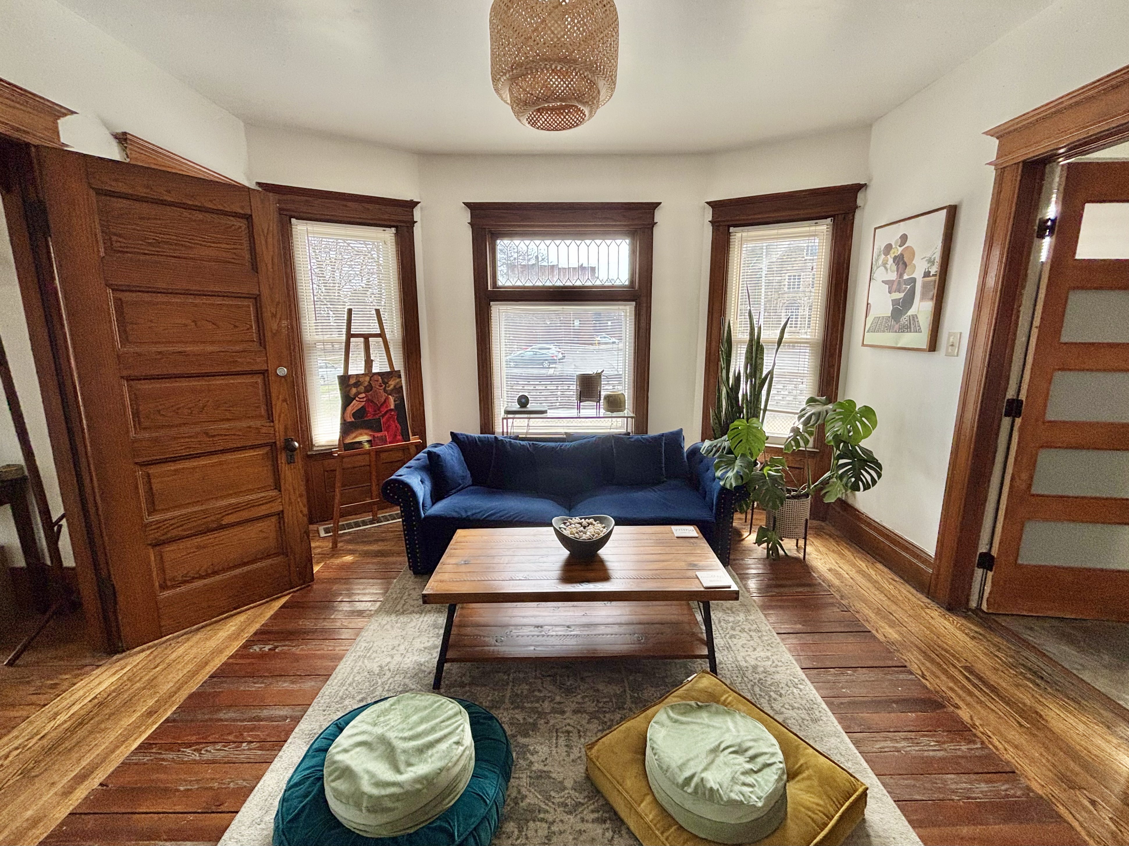 A sitting area with a couch, coffee table, artwork, and plants.